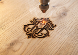 Detalle de grabado láser de alta precisión sobre madera de roble, mostrando un diseño detallado y la textura del material