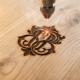Detalle de grabado láser de alta precisión sobre madera de roble, mostrando un diseño detallado y la textura del material