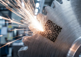 Grabado láser de un código QR en una pieza metálica industrial, imagen de portada para el artículo sobre trazabilidad en el sector industrial de CUSTOM3D.